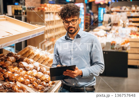 Fresh bakery. Male worker is in the grocery store 136757648