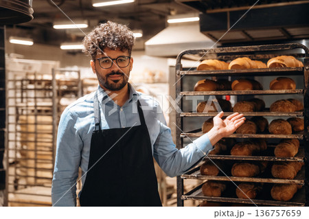Bakery worker in apron is standing indoors 136757659