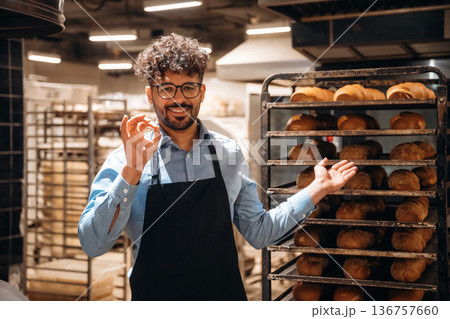 Bakery worker in apron is standing indoors Bakery worker in apron is standing indoors 136757660