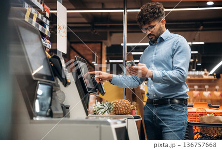 By cash register. Man is in the grocery store 136757668
