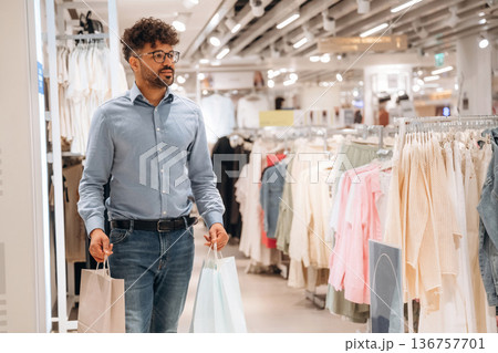 With shopping packages. Man customer is in the clothing store 136757701