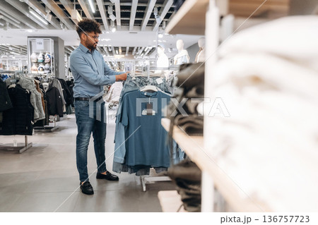 Sweaters section. Man customer is in the clothing store 136757723