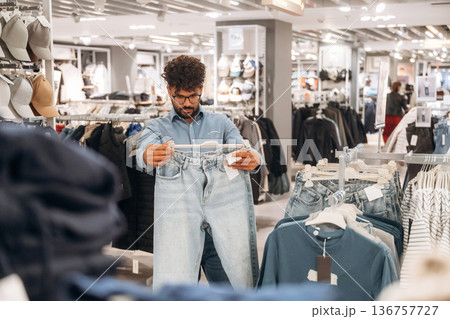 Blue jeans. Man customer is in the clothing store 136757727