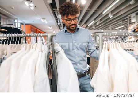 Looking and choosing. Man customer is in the clothing store 136757787