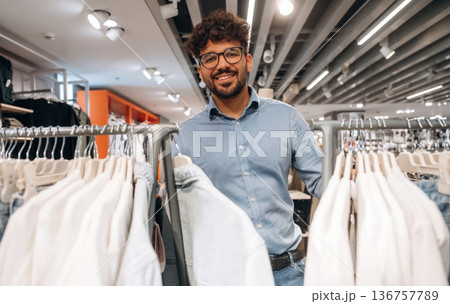 Looking and choosing. Man customer is in the clothing store Looking and choosing. Man customer is in the clothing store 136757789