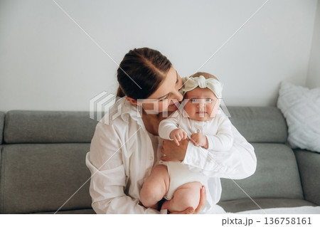 On the gray sofa. Woman is with her little toddler baby daughter 136758161