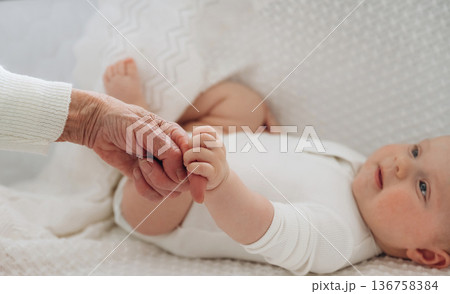Senior woman is holding hands with little baby 136758384