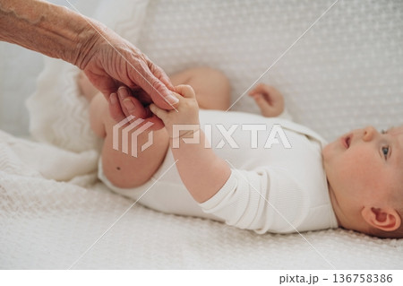Senior woman is holding hands with little baby Senior woman is holding hands with little baby 136758386