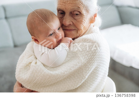 Embracing the toddler. Grandmother with cute toddler baby at home Embracing the toddler. Grandmother with cute toddler baby at home 136758398