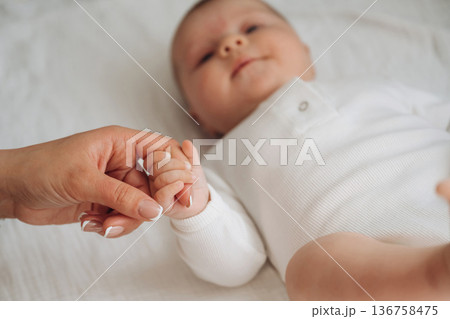 Love and care conception. Close up view of mother and little baby holding hands 136758475