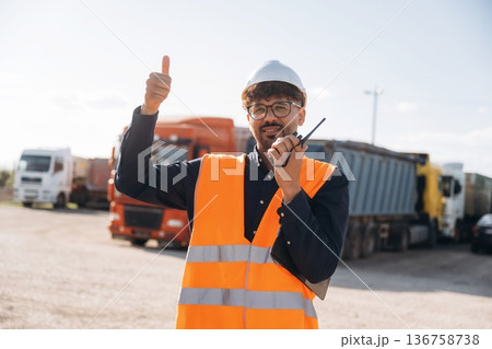 Conversation by using walkie talkie. Male worker is near truck outdoors 136758738