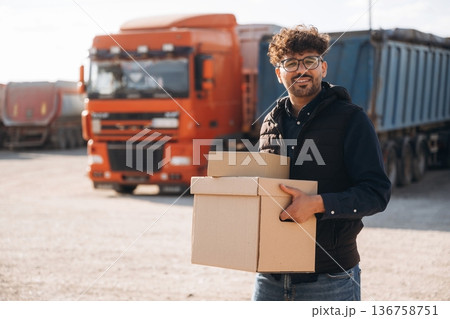 The delivery is in the boxes. Male worker is near truck outdoors The delivery is in the boxes. Male worker is near truck outdoors 136758751