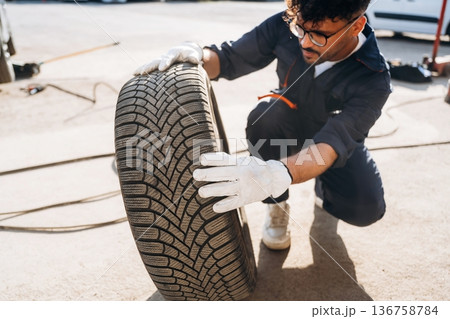 Checking the tire. Mechanic is with the car outdoors Checking the tire. Mechanic is with the car outdoors 136758784