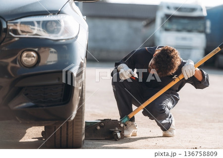 Ready to change the tire. Mechanic is with the car outdoors 136758809
