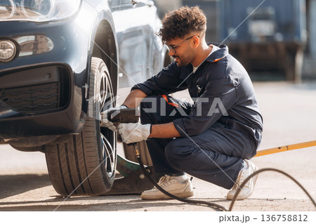 Process of changing the tire. Mechanic is with the car outdoors Process of changing the tire. Mechanic is with the car outdoors 136758812