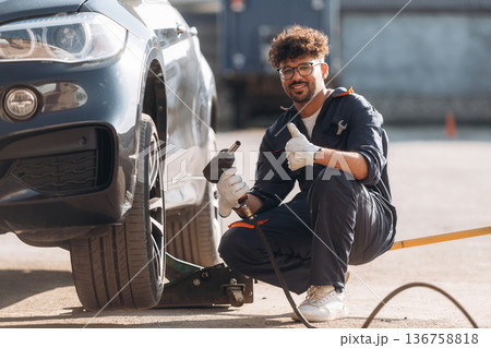 Ready to change the tire. Mechanic is with the car outdoors Ready to change the tire. Mechanic is with the car outdoors 136758818