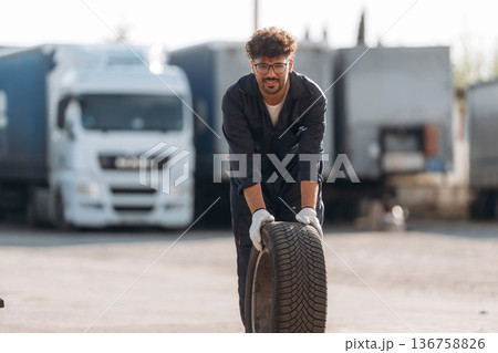 Brand new tire. Male worker is near truck outdoors 136758826