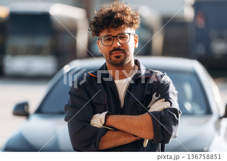 Posing, with arms crossed. Mechanic is with the car outdoors 136758851