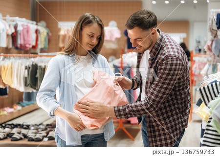Wellbeing, choosing wear. Pregnant woman with man are in the kid's clothing store 136759733