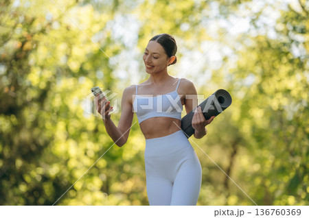 Using phone. Beautiful fitness yoga woman is outdoors, amazing nature Using phone. Beautiful fitness yoga woman is outdoors, amazing nature 136760369