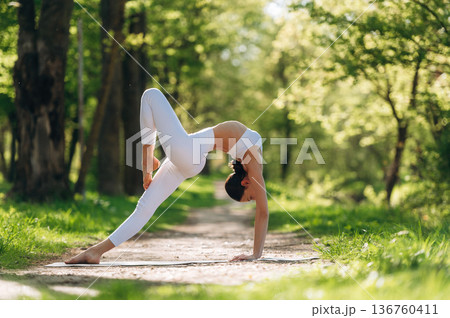Sportive activity, doing exercise. Beautiful fitness yoga woman is outdoors, amazing nature 136760411