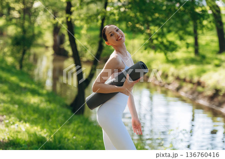 Near the river. Beautiful fitness yoga woman is outdoors, amazing nature 136760416