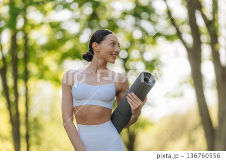 In fitness clothes. Beautiful yoga woman is outdoors, amazing nature In fitness clothes. Beautiful yoga woman is outdoors, amazing nature 136760556
