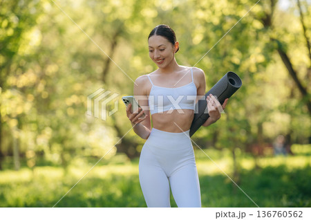 Using phone. Beautiful fitness yoga woman is outdoors, amazing nature Using phone. Beautiful fitness yoga woman is outdoors, amazing nature 136760562