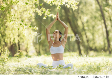On the grass, sitting. Beautiful fitness yoga woman is outdoors, amazing nature 136760616