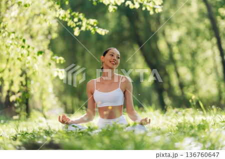 Lotus pose, sitting on the grass. Beautiful fitness yoga woman is outdoors, amazing nature 136760647
