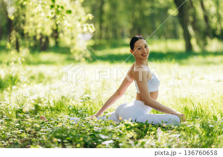 Side view, sitting on the grass. Beautiful fitness yoga woman is outdoors, amazing nature Side view, sitting on the grass. Beautiful fitness yoga woman is outdoors, amazing nature 136760658