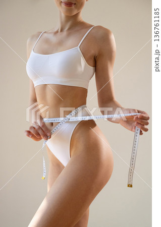 Measuring the waist. Close up view of woman that is in fitness clothes 136761185