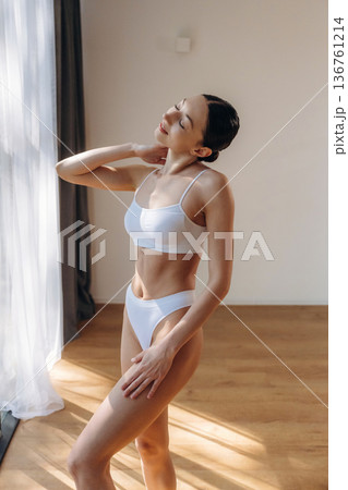 One person is standing in the room. Young woman in fitness clothes One person is standing in the room. Young woman in fitness clothes 136761214