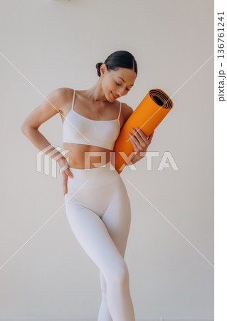 Young woman in sportive clothes is against the wall 136761241
