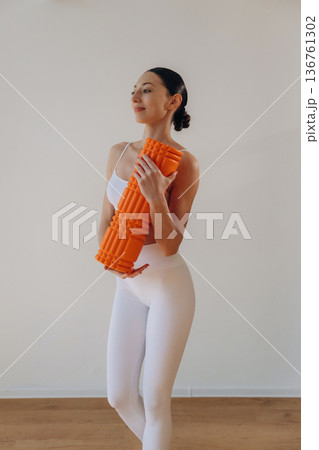 Getting ready for practice, with roll. Young woman in sportive clothes is against the wall 136761302