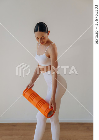 Getting ready for practice, with roll. Young woman in sportive clothes is against the wall Getting ready for practice, with roll. Young woman in sportive clothes is against the wall 136761303