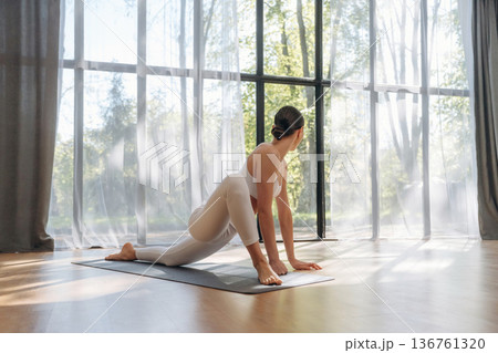 Against the big panoramic window. Young woman in fitness clothes is in the room Against the big panoramic window. Young woman in fitness clothes is in the room 136761320