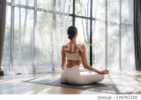 Lotus pose, sitting. Young woman in fitness clothes is in the room Lotus pose, sitting. Young woman in fitness clothes is in the room 136761326