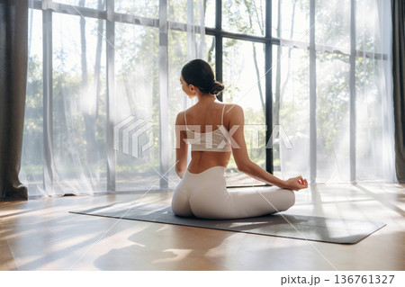 Lotus pose, sitting. Young woman in fitness clothes is in the room Lotus pose, sitting. Young woman in fitness clothes is in the room 136761327