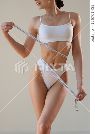 Diet conception. Measuring the waist. Close up view of woman that is in fitness clothes 136761453