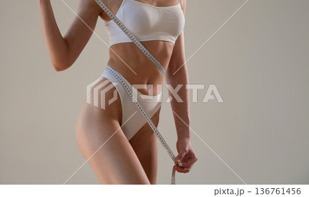 Focused view, measuring the waist. Close up view of woman that is in fitness clothes Focused view, measuring the waist. Close up view of woman that is in fitness clothes 136761456