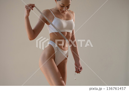 Successful weight loss. Young woman in sportive clothes is against the wall Successful weight loss. Young woman in sportive clothes is against the wall 136761457