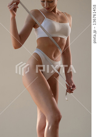 Successful weight loss. Young woman in sportive clothes is against the wall Successful weight loss. Young woman in sportive clothes is against the wall 136761458