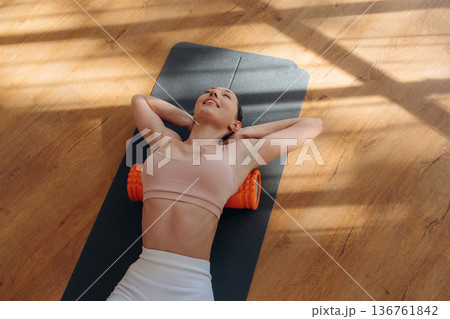 Beautiful sunlight. Woman is doing abs on the yoga mat at home 136761842