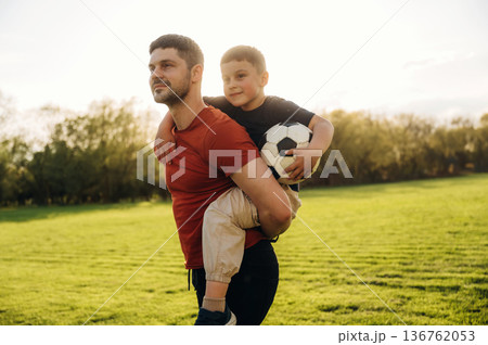 Ready to play soccer, boy is sitting. Father and son are having fun outdoors 136762053