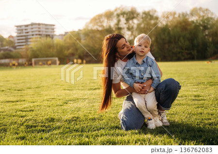 Warm sunlight. Mother and son are together on the summer field 136762083