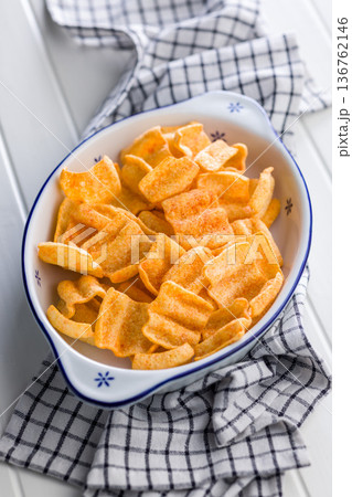 Crispy salted chips in bowl on white table. Crispy salted chips in bowl on white table. 136762146
