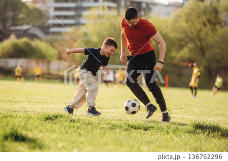 Game of soccer. Father and son are having fun outdoors Game of soccer. Father and son are having fun outdoors 136762296