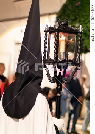 Nazareno holding a traditional lantern during a solemn Holy Week procession at night Nazareno holding a traditional lantern during a solemn Holy Week procession at night 136762677