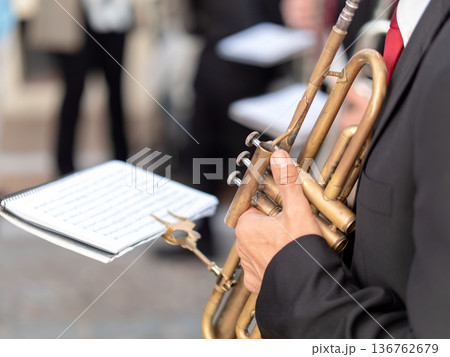 Close up of a musician holding a silver trumpet with sheet music during parade 136762679